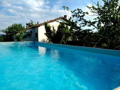 a large blue swimming pool in front of a house at Monte Termine Country House in Rioveggio