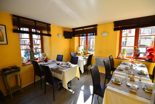 a dining room with tables and chairs and windows at L'Hostellerie du Château in Eguisheim