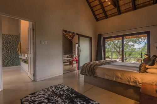 a bedroom with a bed and a large window at BushGlam Luxury Holiday Home in Hoedspruit