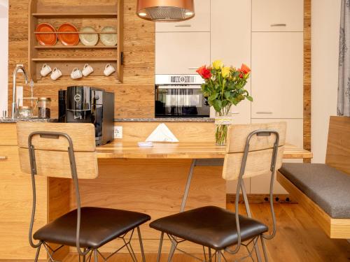a kitchen with a counter with two chairs and a table at Brunnwirt ESSEN & WOHNEN in Fuschl am See