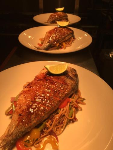 two plates of food with fish and spaghetti on a table at A Park View Hotel in Wolverhampton
