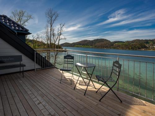 two chairs and a table on a deck overlooking a lake at Brunnwirt ESSEN & WOHNEN in Fuschl am See