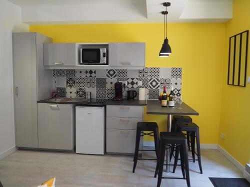 une cuisine avec des appareils électroménagers blancs et une table avec des tabourets dans l'établissement Le Millotet - Agréable studio à 2 mn Dijon Gare, à Dijon