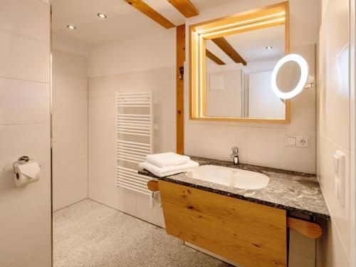 a bathroom with a sink and a mirror at Brunnwirt ESSEN & WOHNEN in Fuschl am See