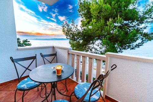 een tafel en stoelen op een balkon met uitzicht op de oceaan bij Sutivan Best Apartments in Sutivan
