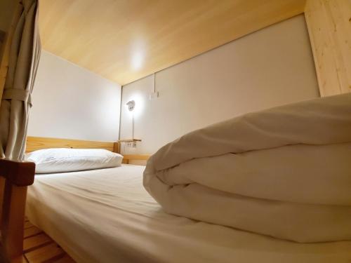 a bedroom with a bed with white sheets at On My Way Taitung Hostel in Taitung City
