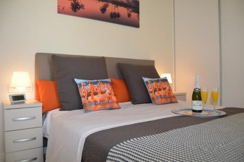 El Mirador de la Ribera - 7408 في سانتياغو دي لا ريبيرا: غرفة نوم مع سرير مع وسائد برتقالية وزجاجة من النبيذ