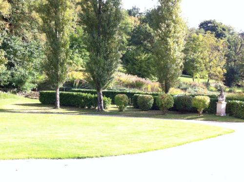 a garden with trees and bushes and a path at La Grande Maison in Seine-Port