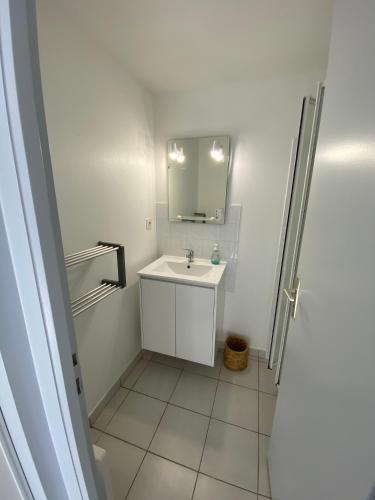 a white bathroom with a sink and a mirror at Maison de vacance proche de la mer in Les Sables-dʼOlonne