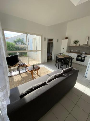 a large living room with a couch and a kitchen at Maison de vacance proche de la mer in Les Sables-dʼOlonne