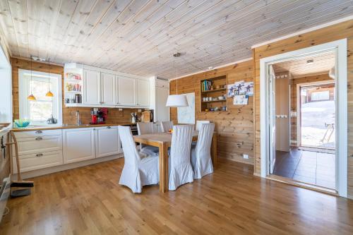 cocina y comedor con mesa y sillas en Three-Bedroom Holiday Cottage en Tjørhom