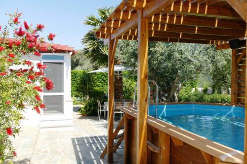 a pool with a wooden pergola next to a house at Esperides in Marathon