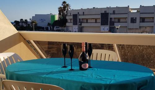 uma garrafa de vinho sentada numa mesa na varanda em Studio Naturiste "LIBERTY" Héliopolis K 125 em Cap d'Agde