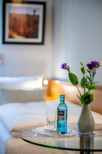 a bottle of water and a glass on a table at Insel Hotel Bonn - Superior in Bonn