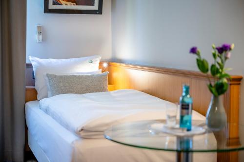 a bed with a glass table with a bottle on it at Insel Hotel Bonn - Superior in Bonn