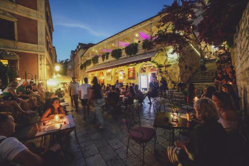 un gruppo di persone seduti ai tavoli in una strada di notte di Heritage Hotel Park Hvar a Hvar