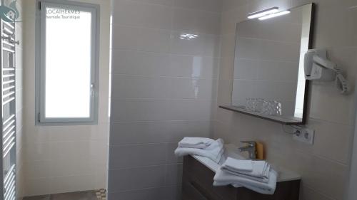 a white bathroom with a sink and a mirror at Calme et Central à Jonzac in Jonzac