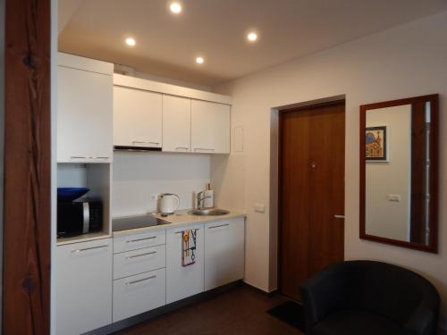 eine Küche mit weißen Schränken und einem schwarzen Stuhl in der Unterkunft ROKO Apartments in Kaunas
