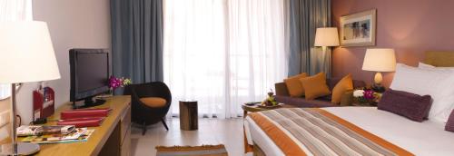a hotel room with a bed and a couch at Mövenpick Resort & Spa Tala Bay Aqaba in Aqaba