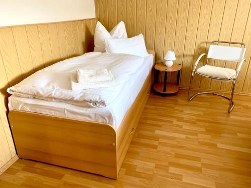 a small bed in a room with a chair at Ferienwohnung Fürstenwalde Spree in Ketschendorf