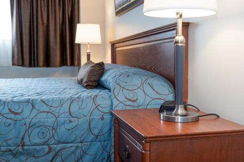 a bedroom with a bed and a lamp on a dresser at Adam's Airport Inn in Ottawa