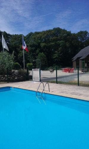 une piscine bleue avec banc et drapeaux dans l'établissement Gite de la Croix du Hêtre, à Hambers