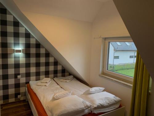 Cama pequeña en habitación con ventana en Apartmenty Magnolia, en Łeba