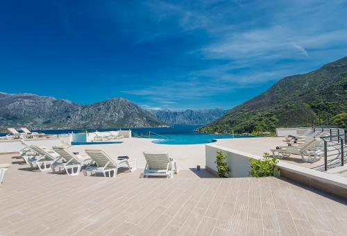 a group of lounge chairs on a patio with a beach at Lavender Bay Apartment E7 in Donji Morinj