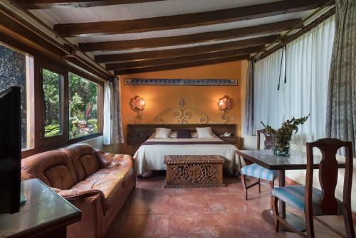 Villa San Jose Hotel & Suites في موريليا: غرفة معيشة مع سرير وأريكة