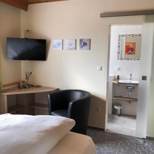 a room with a bed and a chair and a sink at Landgasthof Fischer Veri in Mitterfels