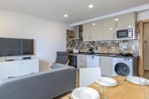 eine Küche und ein Wohnzimmer mit einem Sofa und einem Tisch in der Unterkunft FLH Faro Central House with Terrace in Faro
