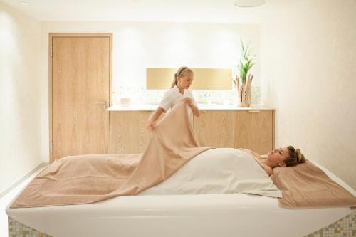 a woman laying on a bed with a girl in a wedding dress at AlpenGold Hotel Davos in Davos