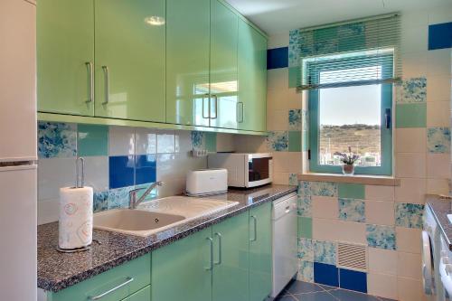 a kitchen with green cabinets and a sink at Marina Sand Residence in Albufeira