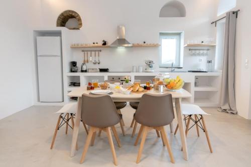 a white kitchen with a table and chairs at Livadi house Tinos in Káto Klísma