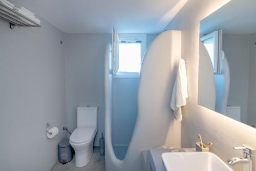 a white bathroom with a toilet and a sink at Livadi house Tinos in Káto Klísma