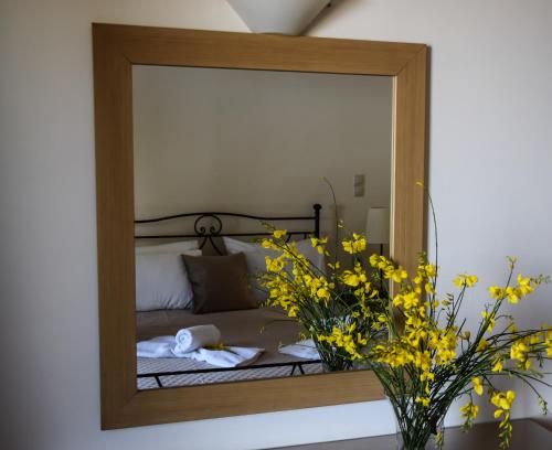 a mirror reflecting a bedroom with a bed and yellow flowers at Marina Pansion in Nydri