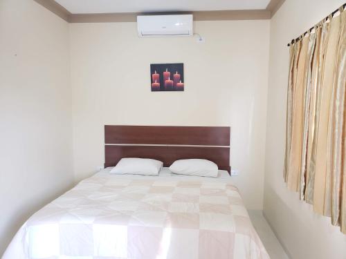 a white bedroom with a bed with a wooden headboard at Felipe Family Houses - Casas de temporada in Foz do Iguaçu