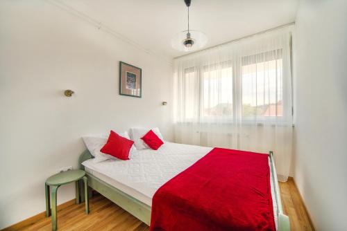 a bedroom with a bed with red pillows and a window at Illy Apartman in Eger