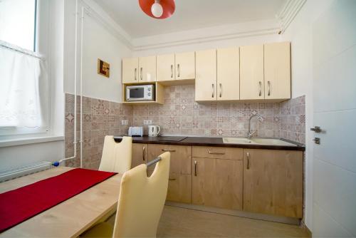 a kitchen with white cabinets and a table and a microwave at Illy Apartman in Eger