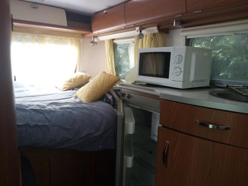 a small kitchen with a bed and a microwave at Havre de paix au bords de l'Eure - divers hébergements in Neuilly