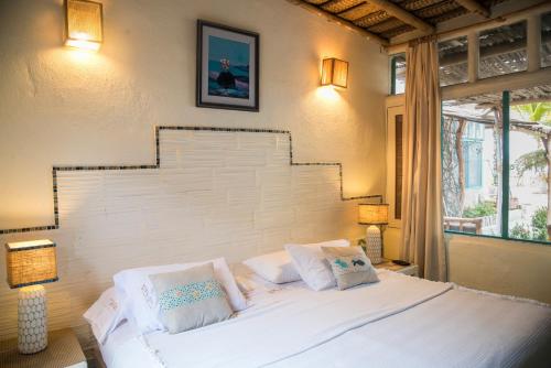 a bedroom with a white bed with two lamps and a window at La Posada De Los Tumpis in Bocapán