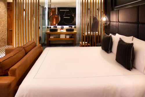 a large white bed in a room with a couch at Diez Diez Collection in Mérida