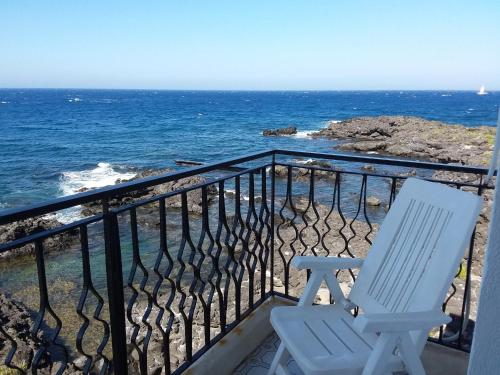 a white chair sitting on a balcony overlooking the ocean at Hotel Orpheus in Giardini Naxos