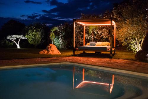 un letto in un gazebo vicino a una piscina di notte di Villa Angel a La Gaude