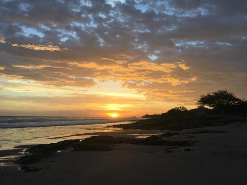 a sunset on a beach with the sun setting at Monoloko Lodge Popoyo in Popoyo