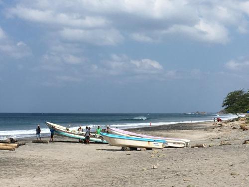 two boats sitting on a beach with the ocean at Monoloko Lodge Popoyo in Popoyo
