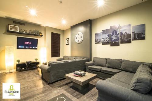 a living room with couches and a clock on the wall at The Clarence Park in Toronto