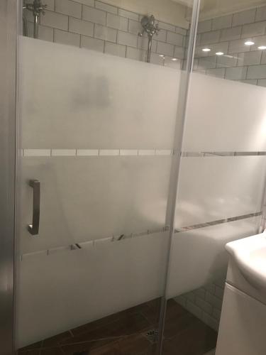 La salle de bains est pourvue d'une porte de douche en verre. dans l'établissement GREG’S BEACH HOUSE, au Cap d'Agde