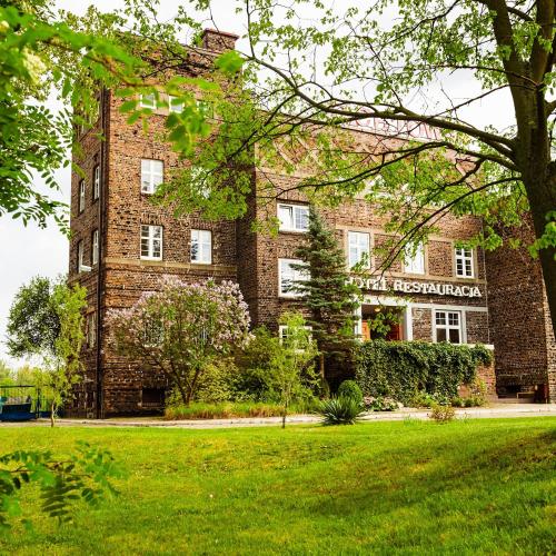 a large brick building with a grass field in front of it at JACHTOWA Hotel i Restauracja in Szczecin