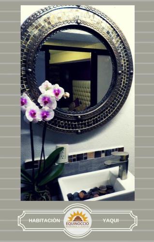 a mirror on a wall with a vase with a flower at Posada Equinoccio in Bernal